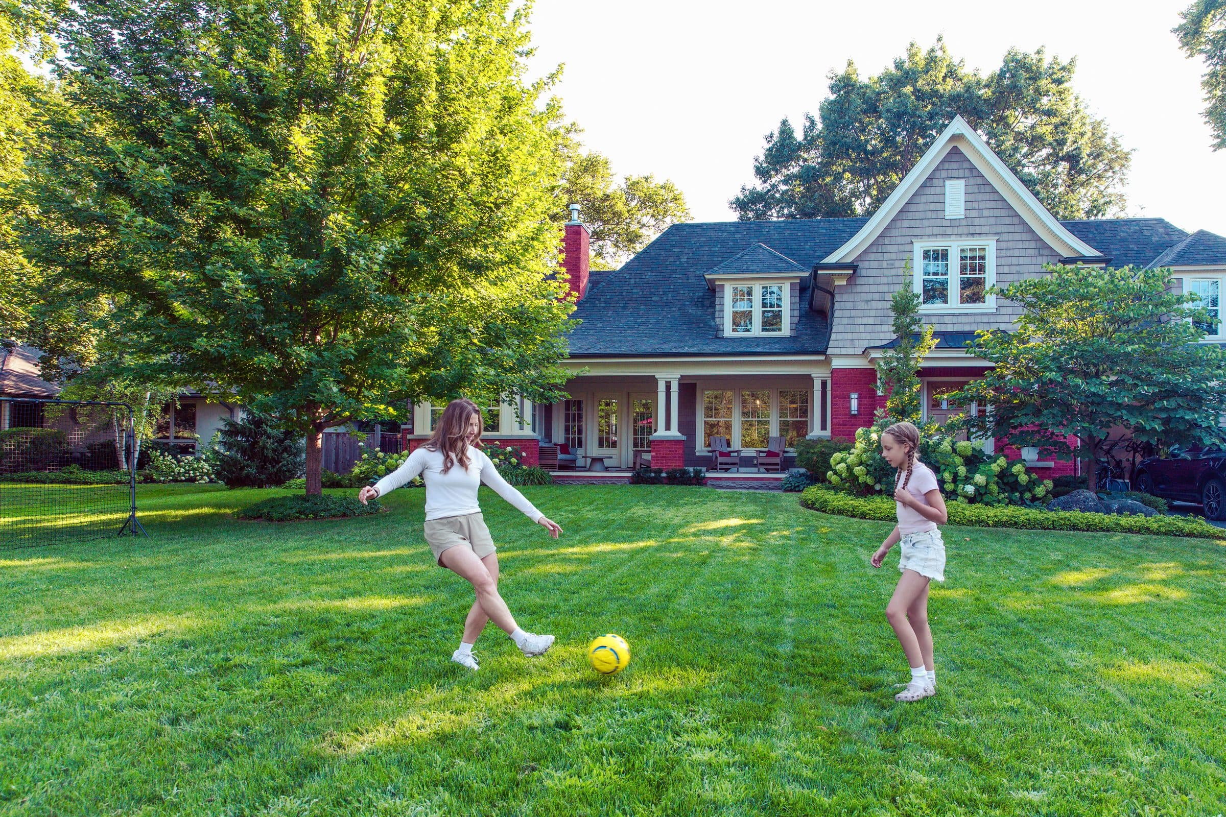 Member playing soccer in the backyard with her daughter